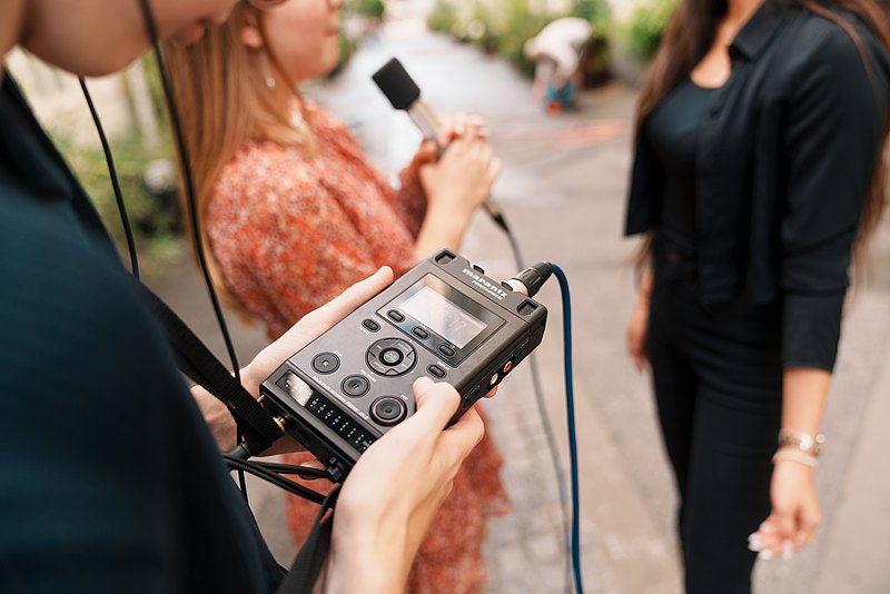 Jugendliche interviewen einander. Im Vordergrund eine Person mit einem Aufnahmegerät