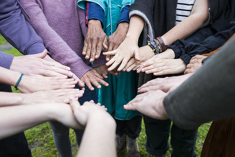 Hände, weiß und of colour, von jungen und älteren Leuten, in einem Kreis aneinander gehalten